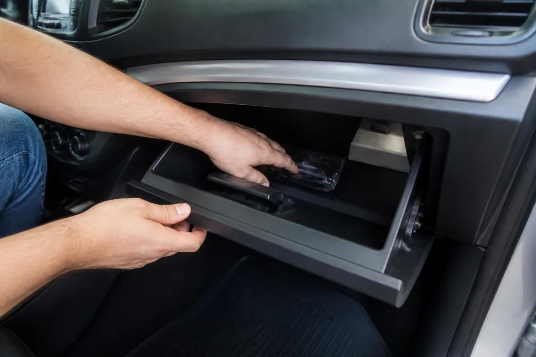 Pessoa procurando o documento do veículo no porta-luvas do carro